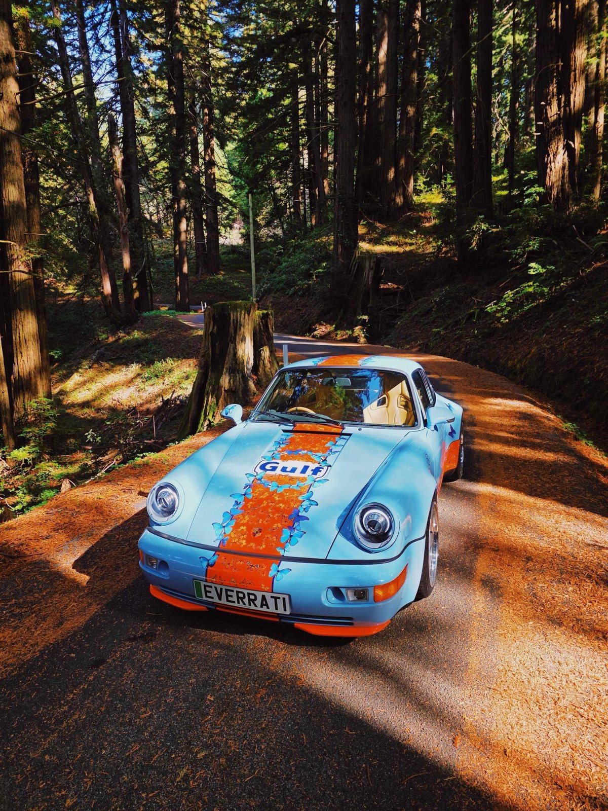 Porsche 911 × Everrati in Gulf blue and orange with butterfly livery, on a forest road